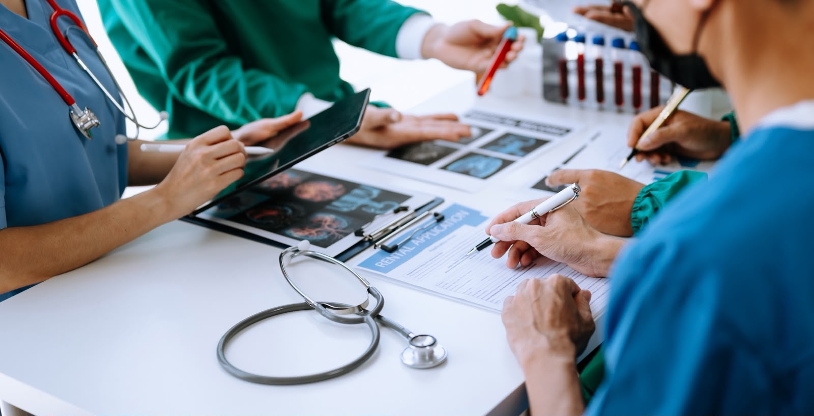 Healthcare professionals reviewing medical records and administrative documents together at a clinical workstation