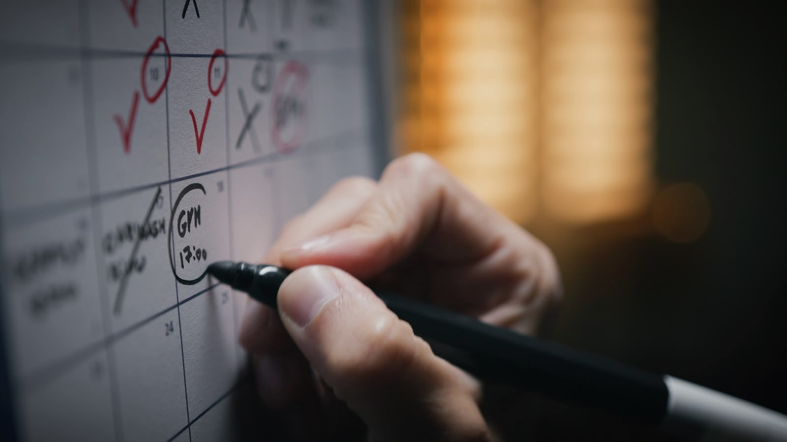 Person planning appointments on a wall calendar with a marker