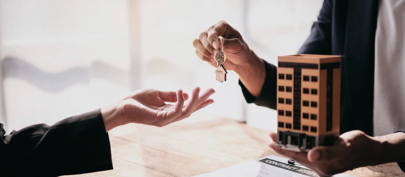 Real estate professional handing house keys to a client during a contract signing