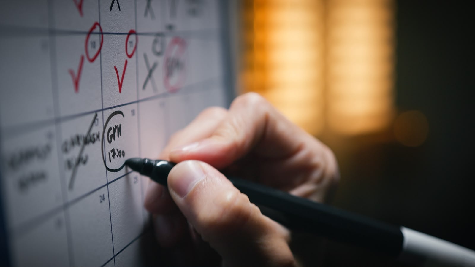 Person marking appointments on a wall calendar with a marker