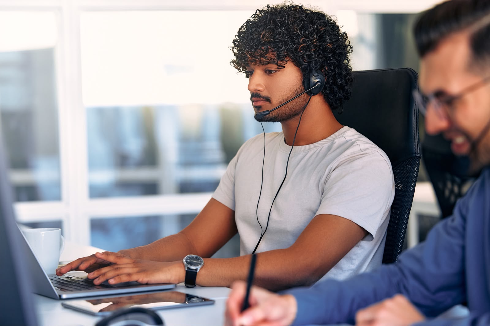 Support professional wearing a headset while managing correspondence on a laptop