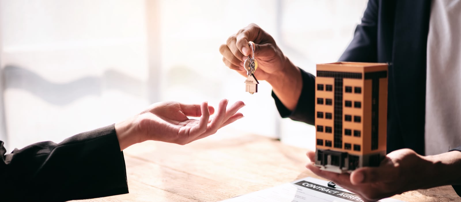 Professional handing over house keys during a contract signing at a desk